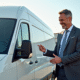Vendeur souriant inspectant une camionnette blanche d'occasion